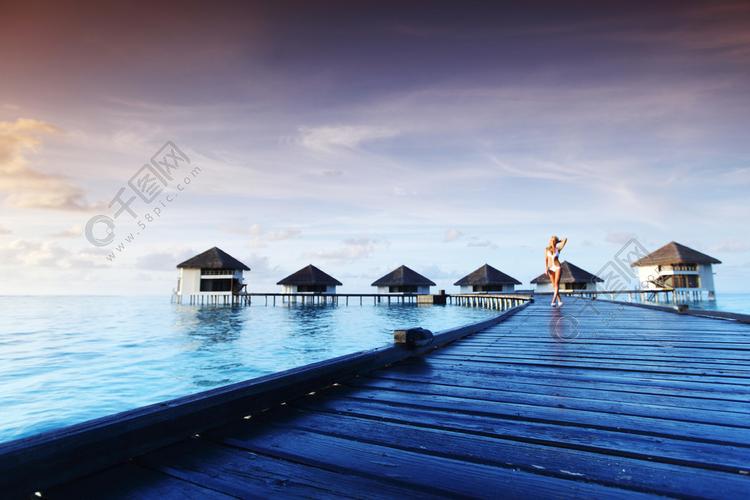 比基尼的女人在桥家海上和背景上的马尔代夫日落马尔代夫日落比基尼的